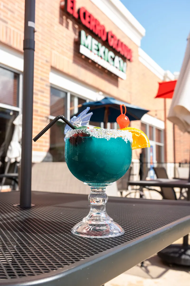 A blue margarita on the patio under the red sign