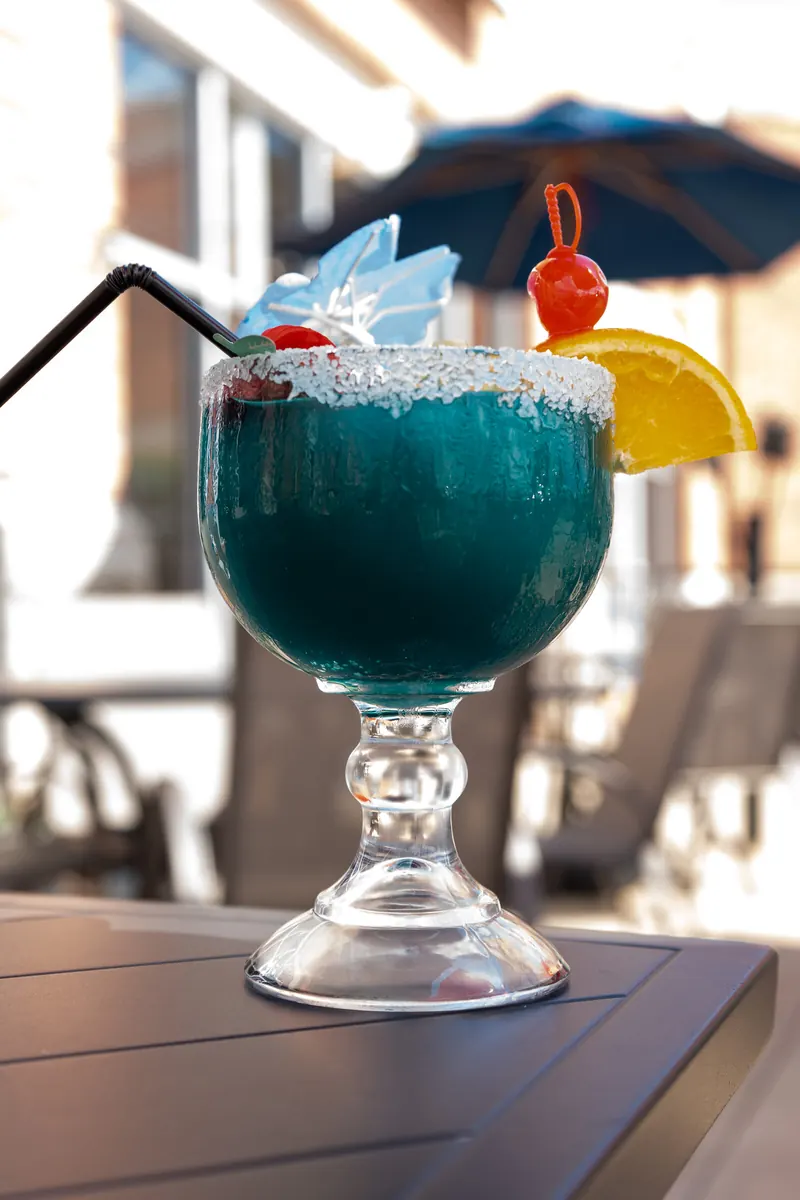 A blue margarita on the patio table under the umbrellas